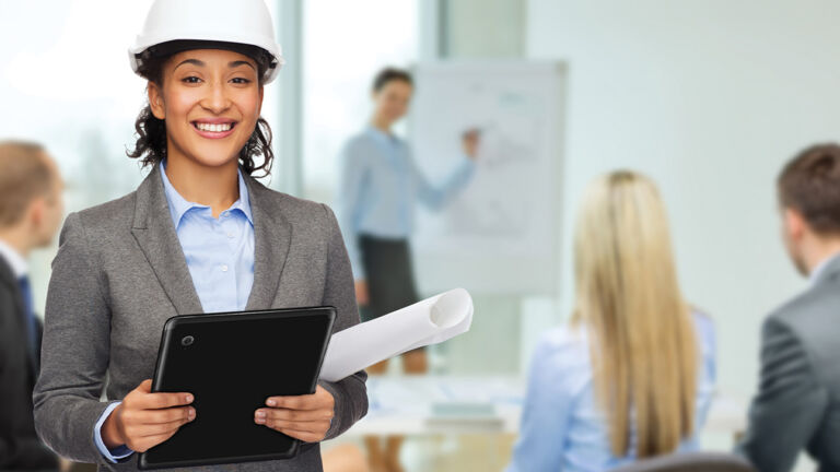 Woman with a hard hat on working in an office on a tablet